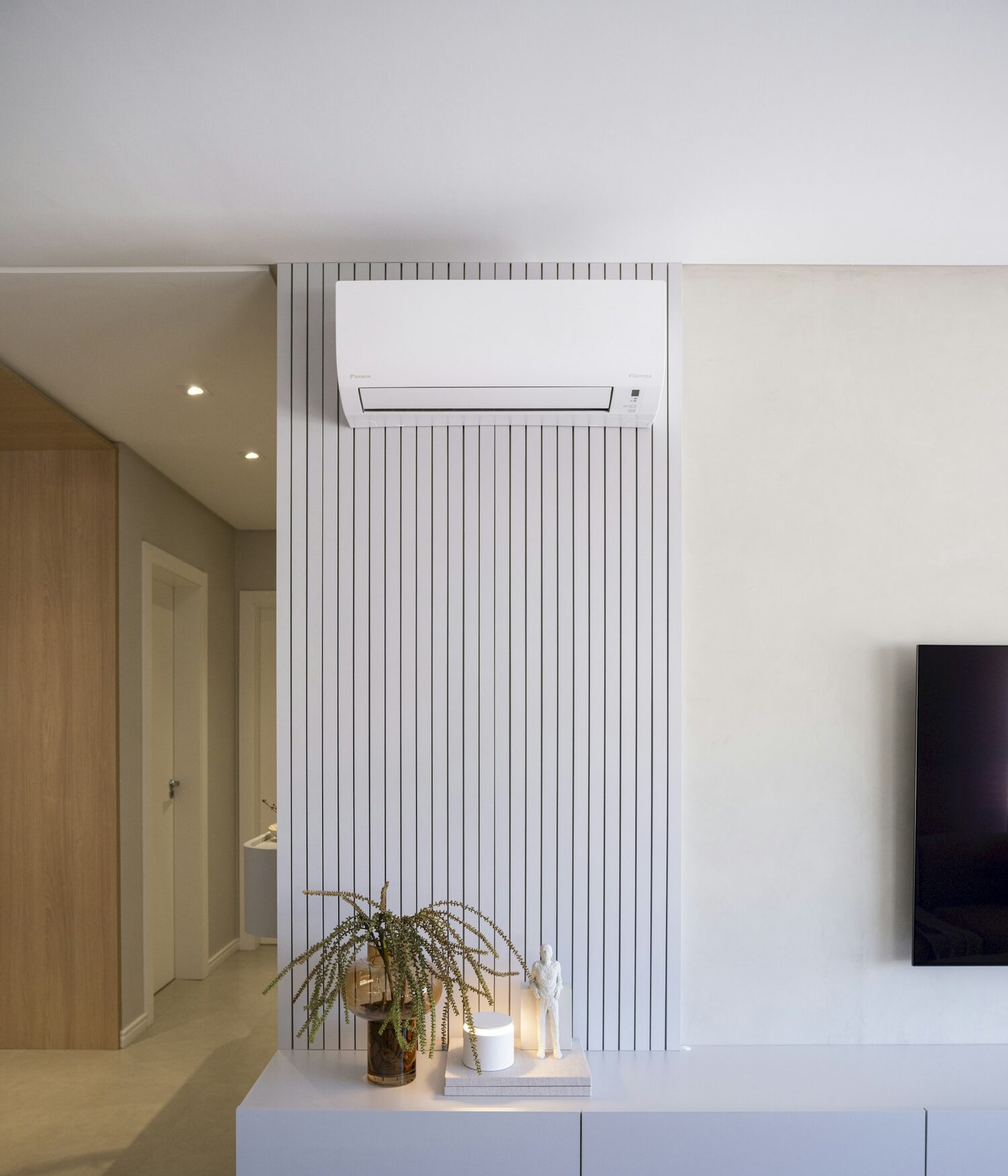 A wall mounted indoor air conditioning unit fitted neatly above a sideboard in a bright modern home
