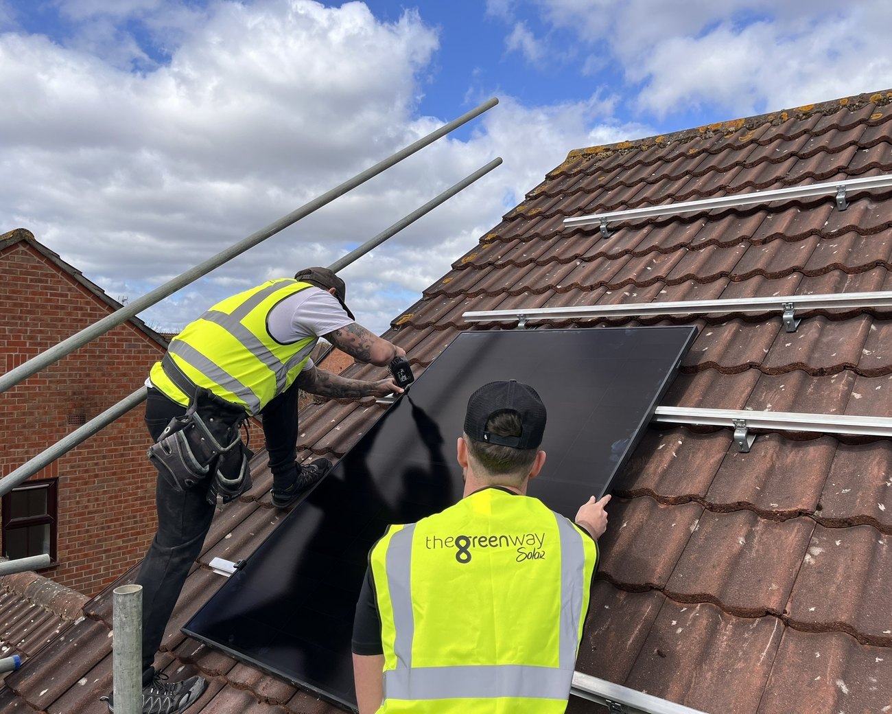 Two Green Way Solar engineers fitting an all-black solar panel on a tiled roof